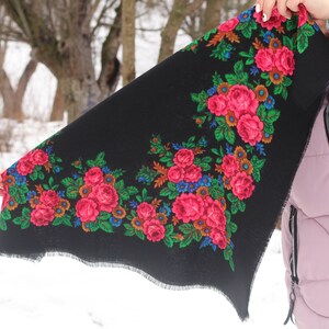 Op de afbeelding: Een zwarte sjaal met een bloemenpatroon met roze, rode, groene en blauwe bloemen. De sjaal heeft een gefranst randje.