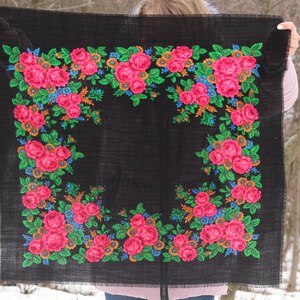 Op de afbeelding: Een zwarte sjaal met een bloemenpatroon van roze, groene, blauwe en oranje rozen. De sjaal is gemaakt van een zachte, geweven stof.
