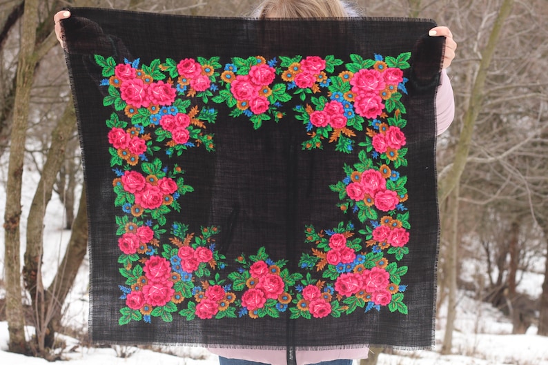 Op de afbeelding: Een zwarte sjaal met een bloemenpatroon van roze, groene, blauwe en oranje rozen. De sjaal is gemaakt van een zachte, geweven stof.