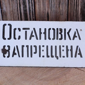 May include: White metal sign with black stenciled text that reads "ОСТАНОВКА ЗАПРЕЩЕНА".