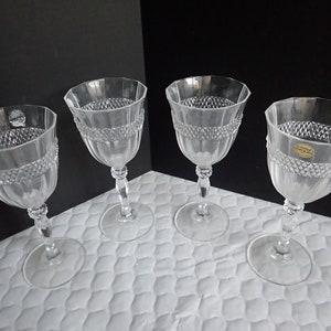 Puede incluir: Juego de cuatro copas de vino de cristal transparente con un patrón de diamante y una banda elevada alrededor del cuenco. Las copas tienen un tallo alto y delgado y una base redonda.