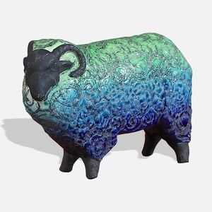 May include: A ceramic sheep sculpture with a black head and horns, and a blue and green glaze. The sheep is standing on four legs.