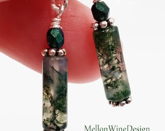 May include: A pair of silver dangle earrings with green moss agate stones and green glass beads. The earrings are approximately 1.5 inches long.