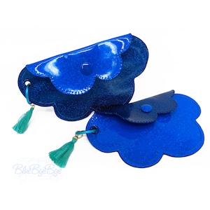May include: Two blue glitter coin purses with a scalloped edge and a tassel. The purses are connected by a gold chain.