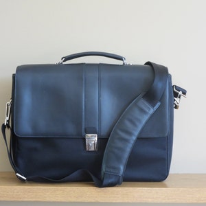 May include: A black leather briefcase with a silver buckle and a black adjustable shoulder strap.