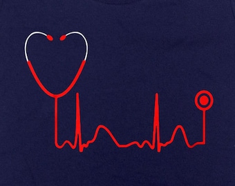 May include: Navy blue t-shirt featuring a red stethoscope design with a heartbeat line. The stethoscope's earpieces form a heart shape. A medical-themed graphic tee for healthcare professionals or medical students.