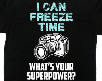 May include: Black t-shirt with the text "I CAN FREEZE TIME" in light blue, above a white illustration of a camera. Below the camera is the text "WHAT'S YOUR SUPERPOWER?"