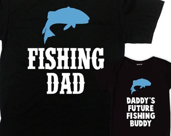 May include: Black t-shirt with a blue fish silhouette and the text "FISHING DAD". A matching black baby onesie with a blue fish silhouette and the text "DADDY'S FUTURE FISHING BUDDY".
