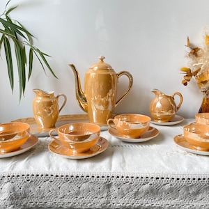 Può includere: Un set da tè vintage di colore giallo dorato caldo. Il set comprende una teiera, un creamer, uno zuccheriera e quattro tazze da tè e piattini.