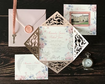 May include: Elegant wedding invitation suite featuring a laser-cut design, floral accents, and a pocket watch. The suite includes an invitation, RSVP card, and envelope with a wax seal. The invitation text reads "Alexandra Spencer Robert Jones".