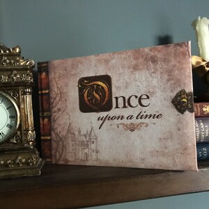 May include: A brown book with the title "Once upon a time" in gold lettering. The book is decorated with a gold key and a castle illustration.
