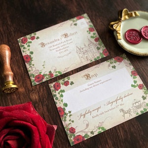 May include: Wedding invitation suite with a vintage aesthetic. The design features a castle illustration, red roses, and ornate script. Includes RSVP cards and a wax seal on a decorative dish. A wooden handled stamp is also present.