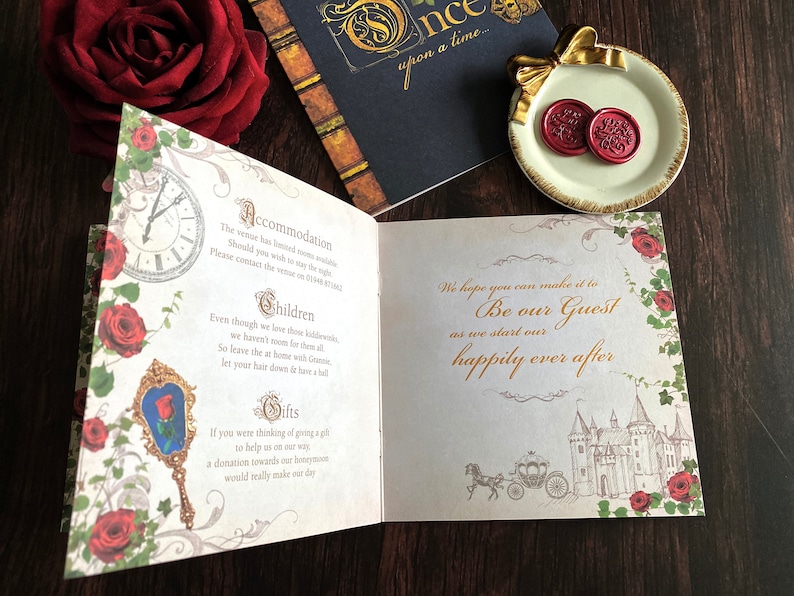 May include: Open invitation card with a fairytale theme. The card features a clock, roses, and a mirror with a rose. The text reads "Be our Guest" and "happily ever after". Includes a small plate with two red wax seals.