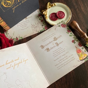 May include: Wedding invitation suite with a fairytale theme. The open invitation features gold script with the names Alexandra Smith and Robert Jones. A red rose and wax seals are also visible.