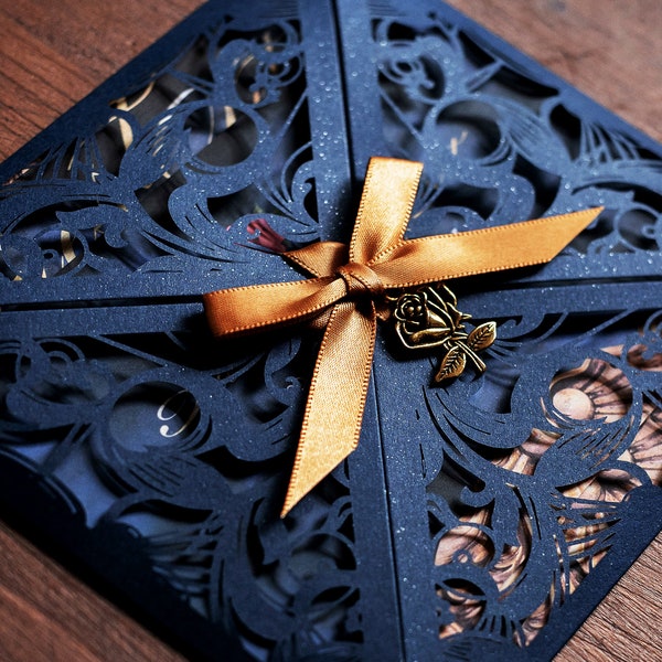 Convite de casamento inspirado em A Bela e a Fera, azul-marinho com corte a laser e laço dourado.