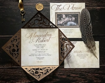 May include: A wedding invitation with a brown and gold intricate design. The invitation features a castle illustration and the text "The Venue", "Peckforton Castle", "Alexandra & Robert", "Together with their families", "would love to invite you", "to their wedding", "Saturday 23rd November 2019", "At Peckforton Castle", "Guest arrival 12.30pm Ceremony at 1pm", "Followed by drinks, wedding breakfast and evening entertainment", "37 June 2019", "189 Basford Park Road", "Newcastle Under Lyme", "Staffordshire", "ST5 0PN".