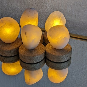 May include: Five white salt lamps with warm, glowing light, each sitting on a natural woven base.