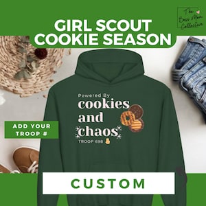 Könnte beinhalten: Grüner Hoodie mit dem Text "Girl Scout Cookie Season" oben und "Powered By cookies and chaos" in der Mitte. Der Text "TROOP 698" befindet sich unter dem Text "chaos". Auf dem Hoodie sind drei Bilder von Girl Scout-Keksen abgebildet. Der Text "CUSTOM" befindet sich unten im Bild.
