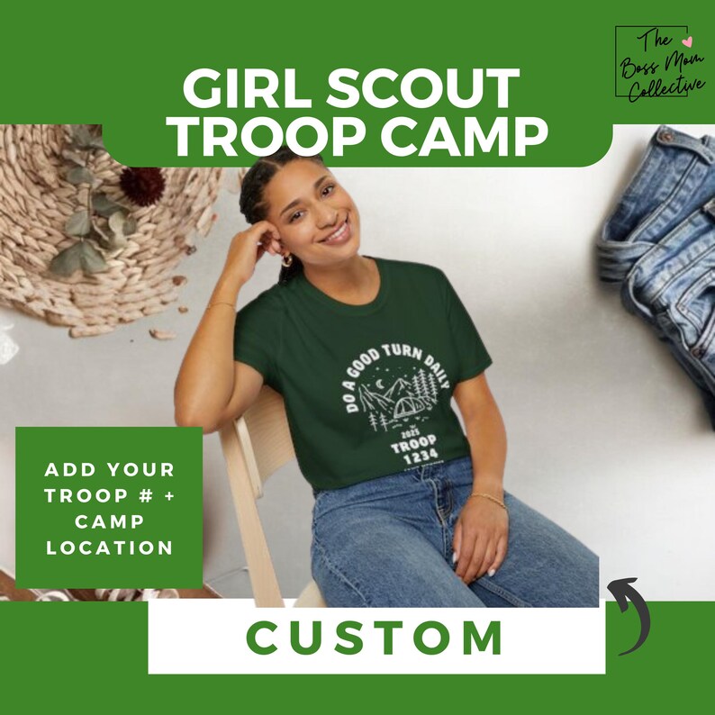 May include: A green t-shirt with a white graphic design that says "Do a good turn daily" and features a camping scene with a tent and trees. The text "2025 Troop 1234" is also included in the design. The t-shirt is being worn by a person sitting on a chair. The text "Girl Scout Troop Camp" is at the top of the image. The text "Add your troop # + camp location" is on the left side of the image. The text "Custom" is at the bottom of the image.