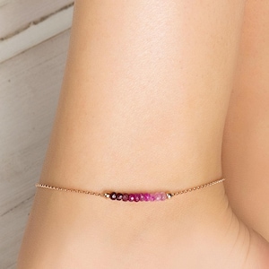 Peut inclure: Un bracelet de cheville en or fin orné d'une rangée de petites pierres précieuses rondes roses et violettes. Le bracelet de cheville est porté autour de la cheville, mettant en valeur l'élégance subtile du bijou. Les pierres sont disposées en ligne.