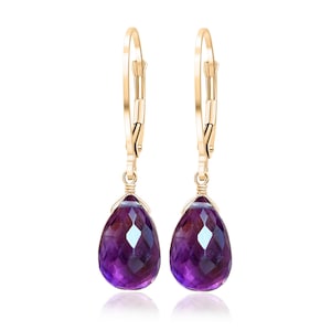 May include: A pair of gold hoop earrings with a teardrop-shaped amethyst gemstone dangling from each hoop.