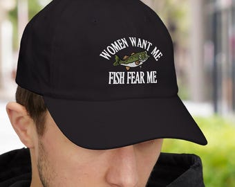 May include: Black baseball cap with the text "WOMEN WANT ME FISH FEAR ME" in white and a green and white fish graphic. The cap has a curved brim and is made of a soft material.