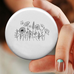 May include: A white round nail stamping plate with a design of flowers and leaves. The design includes the words "F U C K  Y O U R  H I P".