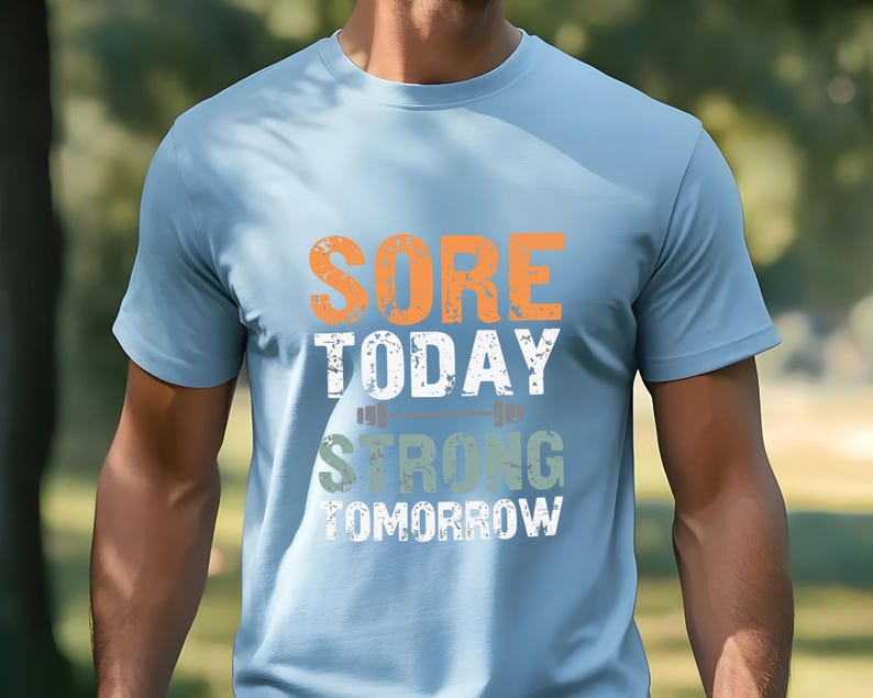 May include: A light blue t-shirt with the text "SORE TODAY STRONG TOMORROW" in orange, white, and green. The text is stylized to look like a distressed, vintage design.