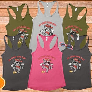 May include: A collection of six racerback tank tops in various colors, including olive green, gray, and pink. Each tank top features a cartoon raccoon graphic with the text "NO FAUX KING WAY" and "USA".
