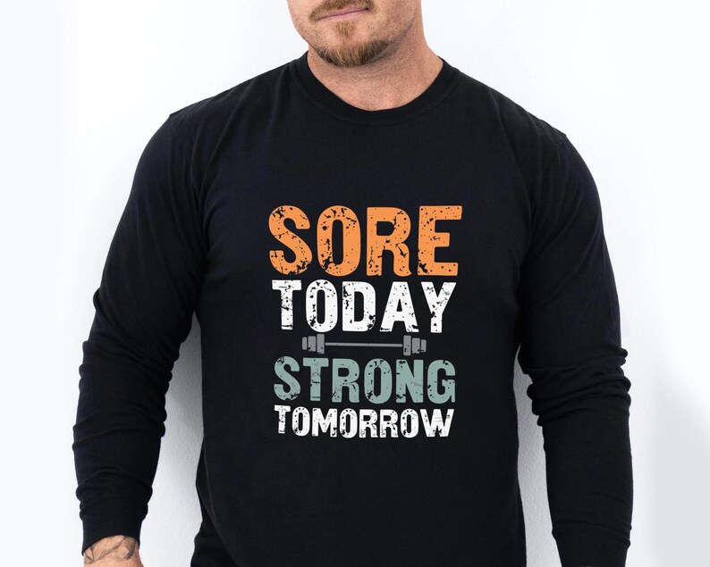 May include: Black long-sleeve shirt with the text "Sore Today Strong Tomorrow" in orange and green with a barbell graphic.