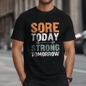 May include: Black t-shirt with a white graphic that says "Sore Today Strong Tomorrow" with a barbell graphic between the words.