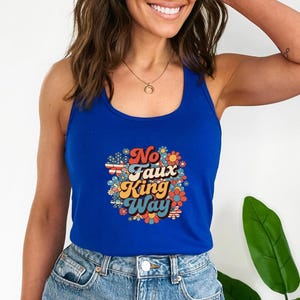 May include: A royal blue tank top with a colorful floral design and the text "No Faux King Way". The graphic includes red, white, and blue elements. The tank top is made of a soft material.
