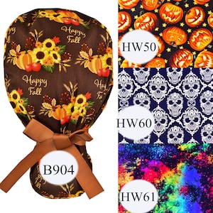 May include: A brown fabric scrub hat with a bow and the text "Happy Fall" printed on it. The hat is tied with a brown ribbon. There are three different fabric patterns to choose from: a pumpkin and star pattern, a skull and crossbones pattern, and a colorful splatter pattern.