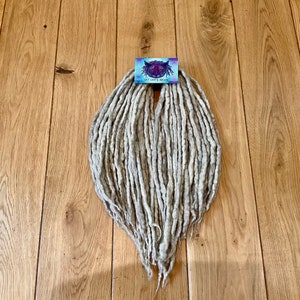 Könnte beinhalten: Ein Bündel hellgrauer Wolldreads, etwa 60 cm lang, mit einem kleinen Etikett mit der Aufschrift "Cat Lady's Dreads".
