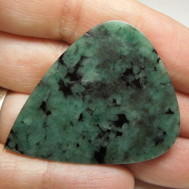 Peut inclure: Un cabochon de pierre pr&eacute;cieuse vert et noir avec un motif unique et mouchet&eacute;. Le cabochon est en forme de larme et a une surface lisse et polie.