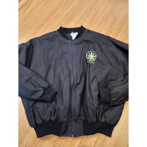 Puede incluir: Chaqueta bomber azul marino con cuello, puños y dobladillo de canalé negro. La chaqueta tiene cierre de cremallera y dos bolsillos delanteros. Un emblema verde y blanco está en el pecho izquierdo, con el texto "Roots to Bring 1995/96".