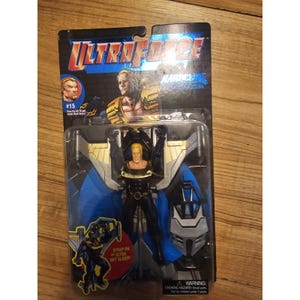 Pode incluir: Figura de ação Ultraforce Marvel Comics, nº 15, na embalagem original. A figura é um homem loiro com um traje preto e dourado com asas azuis. A embalagem inclui o Ultra Sky Glider e um aviso sobre perigo de asfixia.