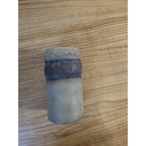 May include: A handcrafted, cylindrical vase with a textured surface. The vase features a light beige base, a dark brown band, and a gray top. The design is simple and rustic, suitable for displaying flowers or as a decorative piece.
