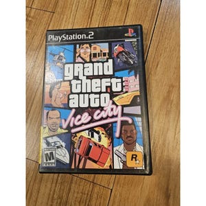May include: A PlayStation 2 video game case for Grand Theft Auto Vice City. The cover features a collage of illustrations including a helicopter, a motorcycle, a yellow sports car, a speedboat, and several characters, with the Mature ESRB rating.