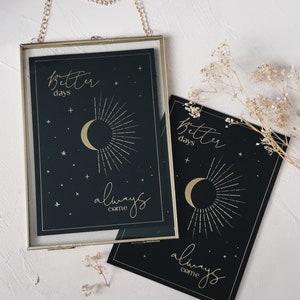 May include: Two black framed prints with gold lettering and illustrations. The top print says "Better days always come" and features a crescent moon with sun rays. The bottom print says "Better days always come" and features a crescent moon with sun rays.