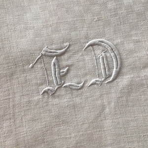 May include: White embroidered initials "ED" on a white linen fabric.