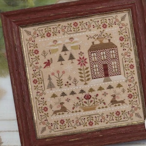 May include: Cross stitch pattern titled "The Light of Winter" by Brenda Gervais, featuring a winter scene with a house, trees, birds, and deer. The pattern is framed in a red wood frame.