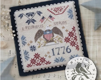 May include: A patriotic cross-stitch design featuring an eagle, American flags, and the year 1776. The design includes the phrase "E PLURIBUS UNUM" and is framed with a navy blue border and white lace trim. A circular design with a bird is in the lower right.