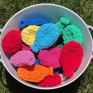 May include: A white bucket filled with colorful crocheted balls. The balls are in various shades of red, pink, blue, yellow, and green.