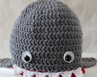May include: Gray crocheted shark hat with white teeth and black button eyes.