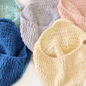 May include: Four crocheted baskets in different colors: blue, light blue, cream, and pink. The baskets are made with a thick yarn and have a soft, textured look.