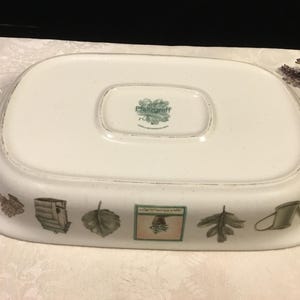 May include: White rectangular serving platter with a decorative border featuring leaf and garden-themed illustrations. The platter has a slightly raised edge and a central recessed area. The underside has a maker's mark.