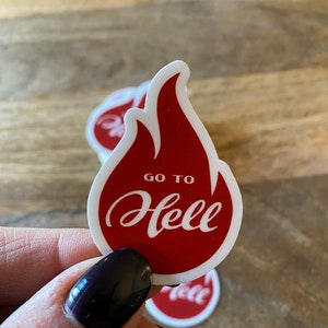 May include: A red and white sticker with a flame design and the text "GO TO HELL" in a white cursive font.