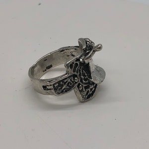 May include: A silver ring featuring a detailed saddle design. The ring is made of metal and has a polished finish.