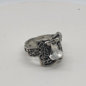 May include: A silver ring featuring an intricate design of a saddle. The ring is crafted from metal and has a polished finish.